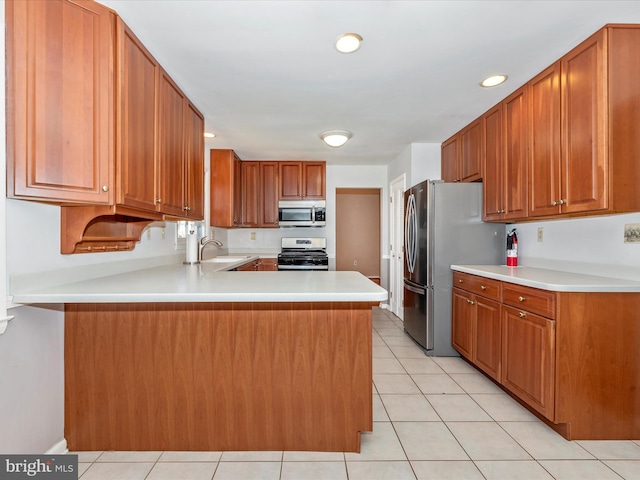 kitchen with a peninsula, light tile patterned floors, light countertops, and appliances with stainless steel finishes