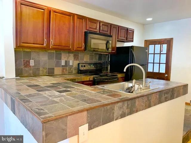 kitchen with tile countertops, black appliances, tasteful backsplash, and a sink