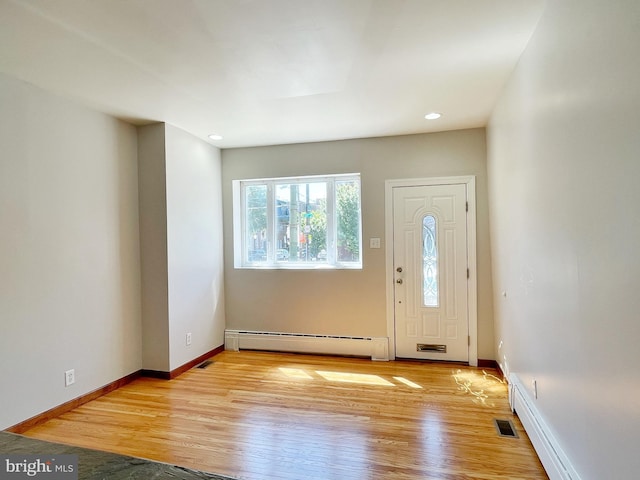 foyer with a baseboard heating unit, light wood-type flooring, visible vents, and baseboards