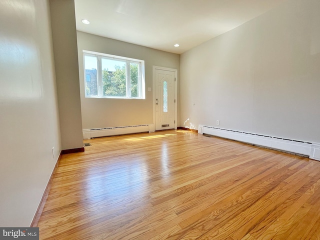 unfurnished room featuring a baseboard heating unit, baseboards, light wood-style flooring, and recessed lighting