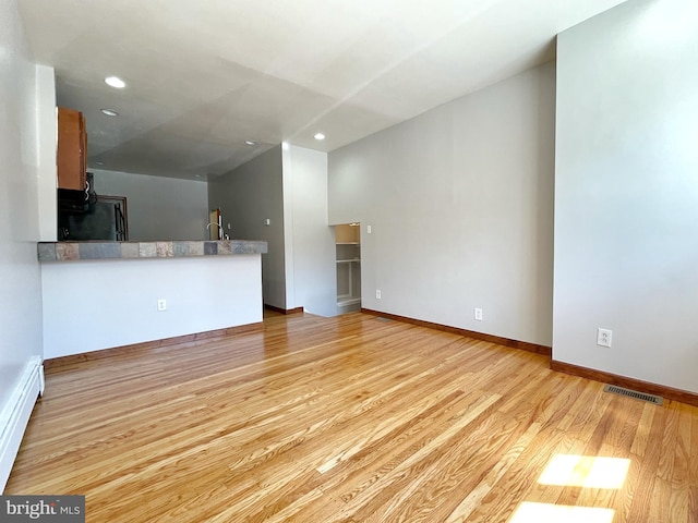 unfurnished living room with baseboards, visible vents, light wood-type flooring, a baseboard heating unit, and recessed lighting