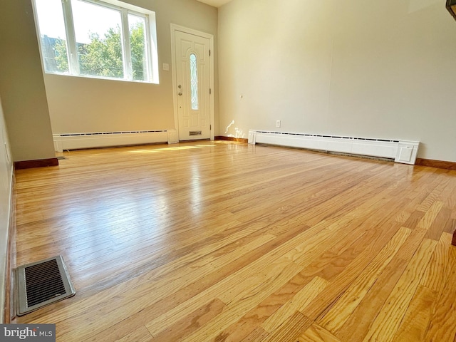 interior space featuring baseboards, visible vents, baseboard heating, and wood finished floors