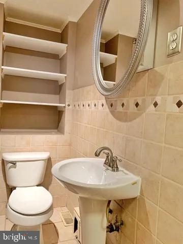 half bathroom with tile walls, toilet, and tile patterned floors