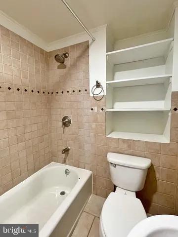 bathroom featuring toilet, tub / shower combination, tile walls, and tile patterned floors