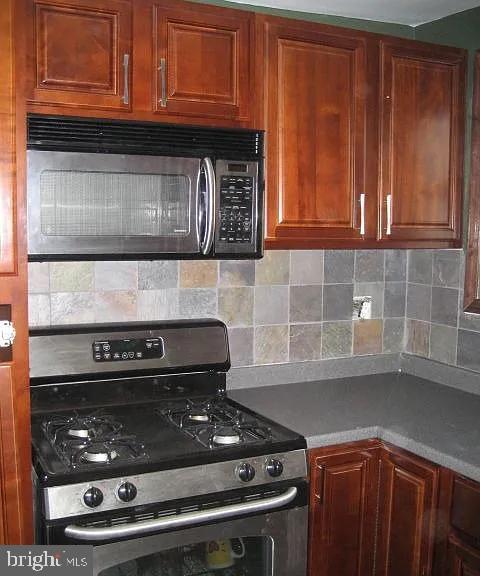 kitchen with stainless steel gas stove, tasteful backsplash, and brown cabinetry