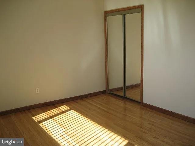 unfurnished bedroom with a closet, wood finished floors, and baseboards