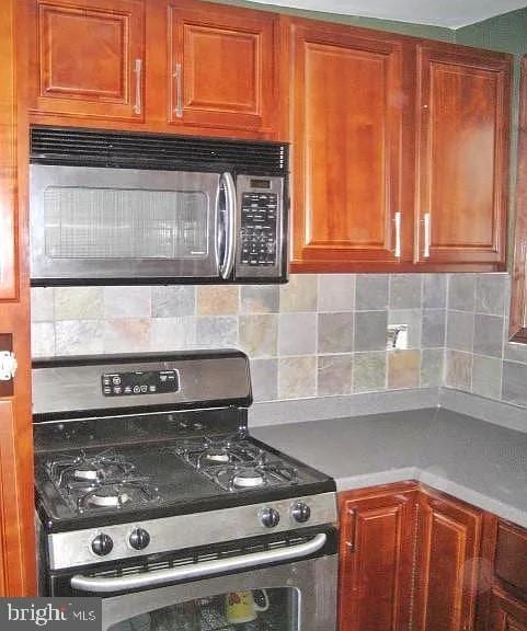 kitchen featuring light countertops, appliances with stainless steel finishes, backsplash, and brown cabinets