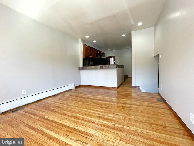 unfurnished living room featuring baseboard heating, light wood-type flooring, and recessed lighting