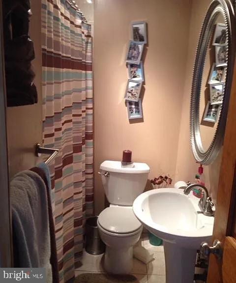 bathroom featuring tile patterned flooring, a shower with shower curtain, and toilet