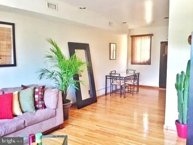 living room featuring baseboards, visible vents, and wood finished floors