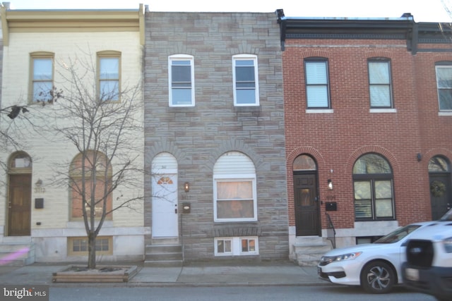 townhome / multi-family property featuring entry steps, stone siding, and brick siding