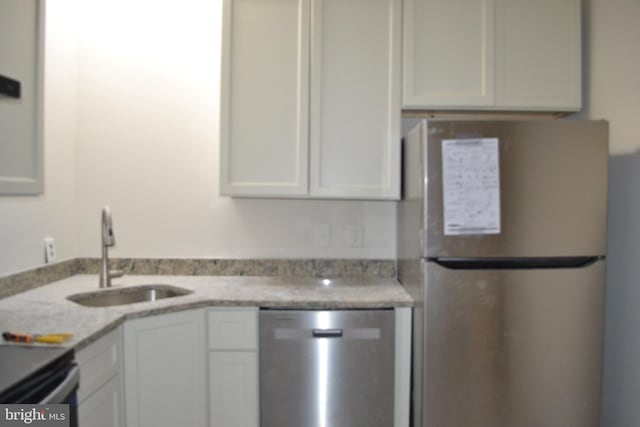 kitchen with appliances with stainless steel finishes, a sink, and white cabinetry