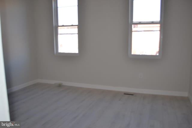 spare room featuring visible vents, baseboards, and wood finished floors