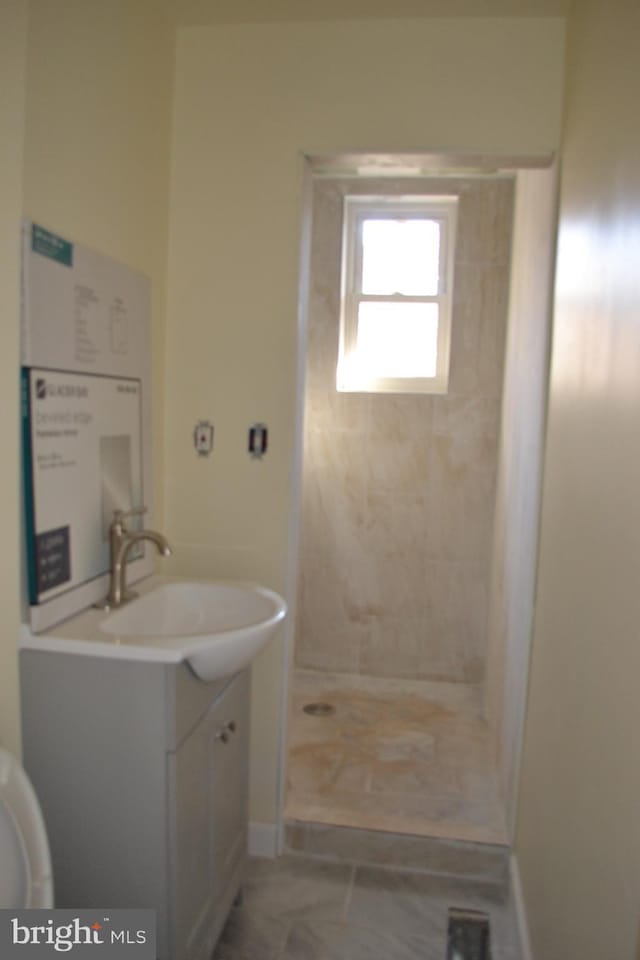 full bath featuring a tile shower, vanity, and toilet