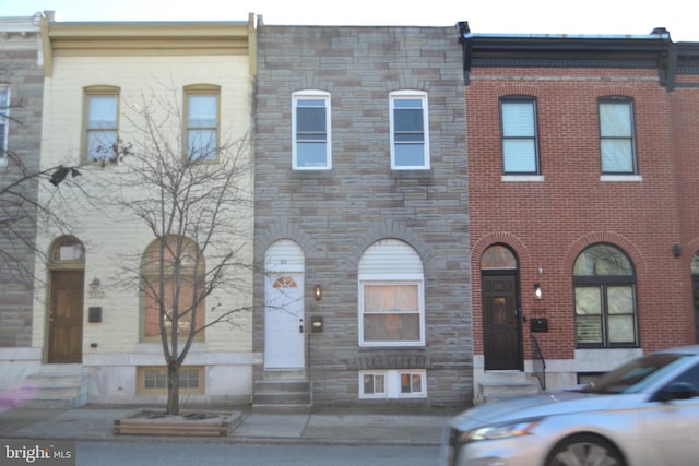 multi unit property featuring entry steps, stone siding, and brick siding