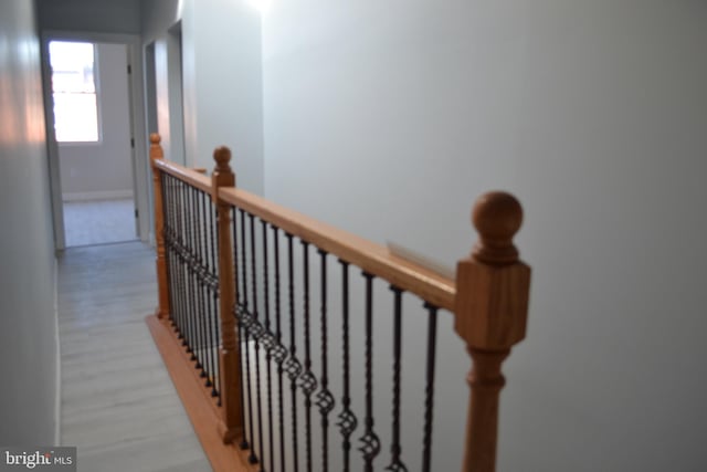 corridor with an upstairs landing, light wood-style flooring, and baseboards