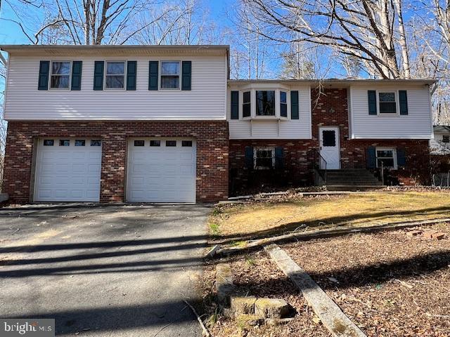 bi-level home with aphalt driveway, brick siding, and a garage