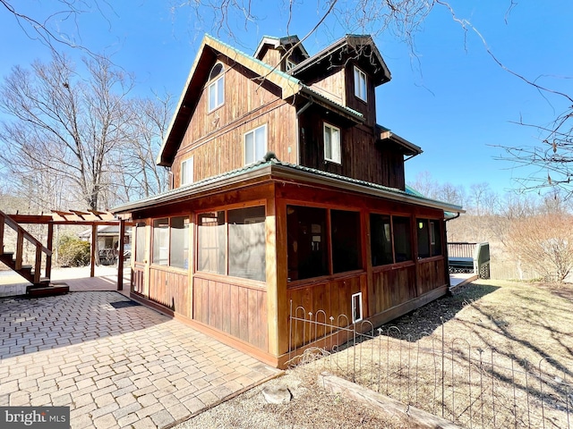 view of side of home with a sunroom and a patio area