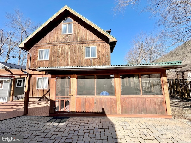 rear view of property featuring a sunroom and a deck