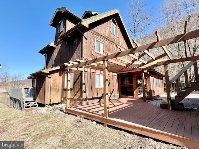 rear view of property featuring a deck and a pergola
