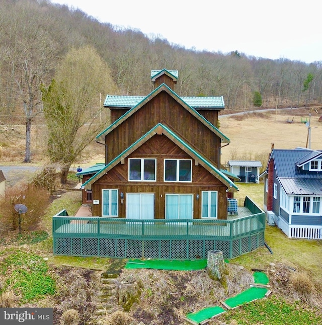 rear view of property with a deck and a view of trees