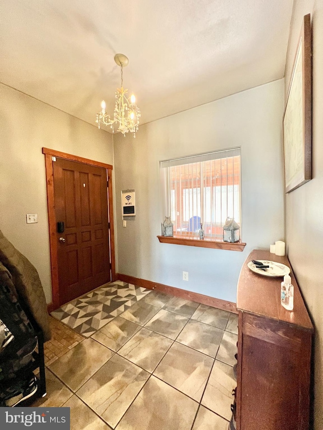 foyer with baseboards, tile patterned flooring, and an inviting chandelier