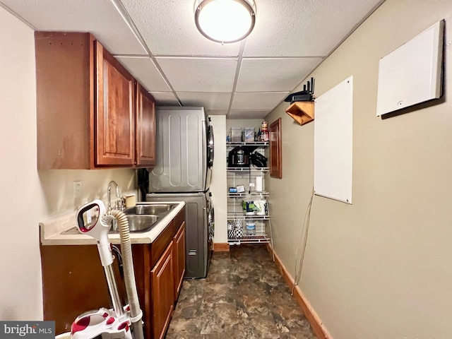 washroom featuring stacked washer and dryer, a sink, and baseboards