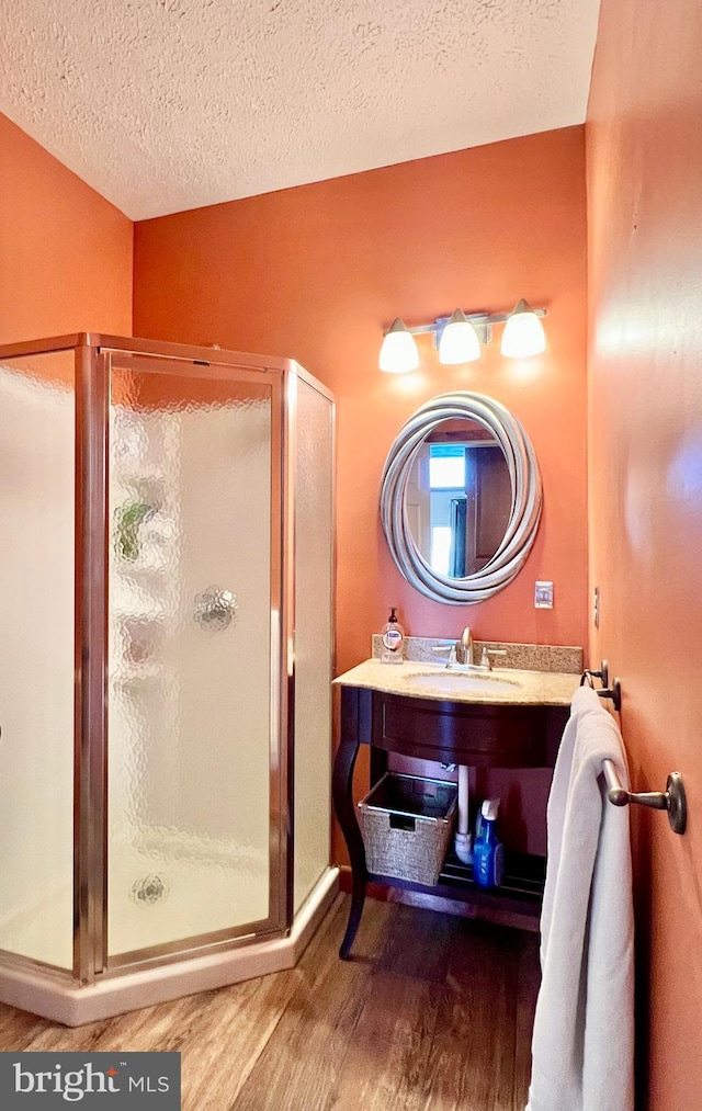 full bath featuring a sink, a shower stall, and wood finished floors