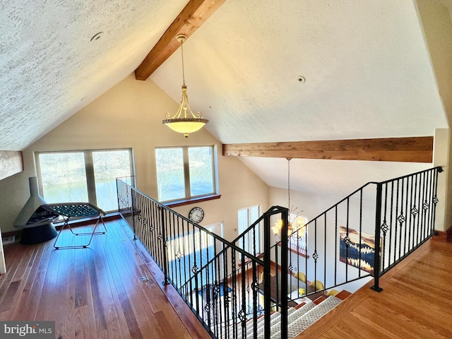 interior space with wood-type flooring, a textured ceiling, high vaulted ceiling, and beam ceiling