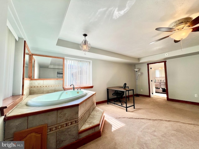 bathroom featuring baseboards, a tray ceiling, ceiling fan, and a bath