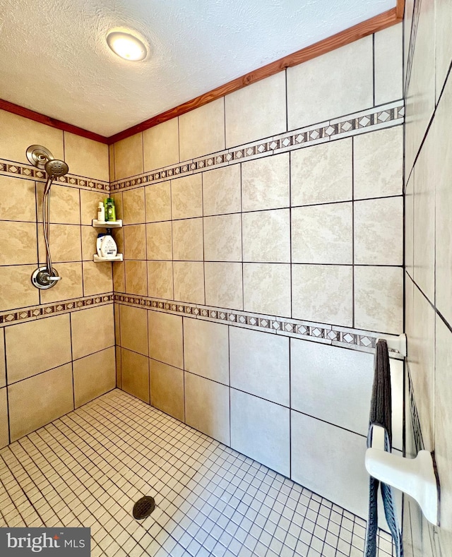 full bathroom featuring a textured ceiling and tiled shower