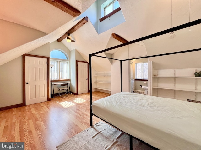 unfurnished bedroom featuring lofted ceiling with beams, baseboards, and wood finished floors