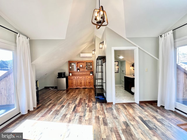 interior space featuring lofted ceiling, an AC wall unit, dark wood finished floors, and baseboards