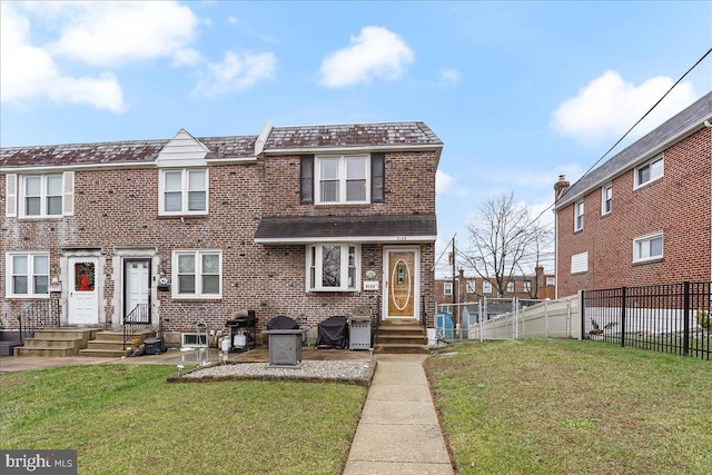 townhome / multi-family property with fence, a front lawn, and brick siding