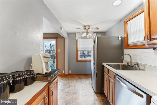 kitchen with decorative backsplash, stainless steel appliances, a sink, and light countertops