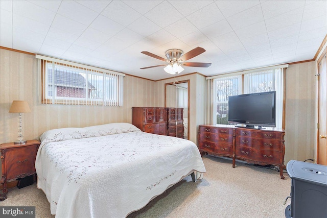 bedroom featuring carpet floors, wallpapered walls, ceiling fan, and crown molding