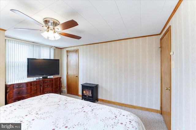 carpeted bedroom featuring a wood stove, wallpapered walls, baseboards, and crown molding