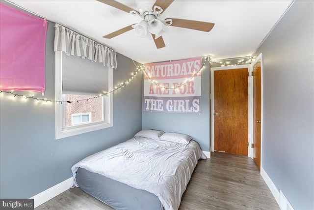 bedroom featuring a ceiling fan, baseboards, and wood finished floors