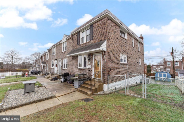 view of front of home with brick siding, a front yard, fence, and a gate