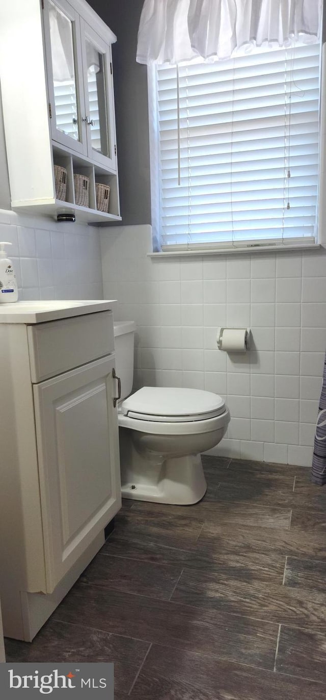 bathroom featuring toilet, tile walls, wood finished floors, and vanity