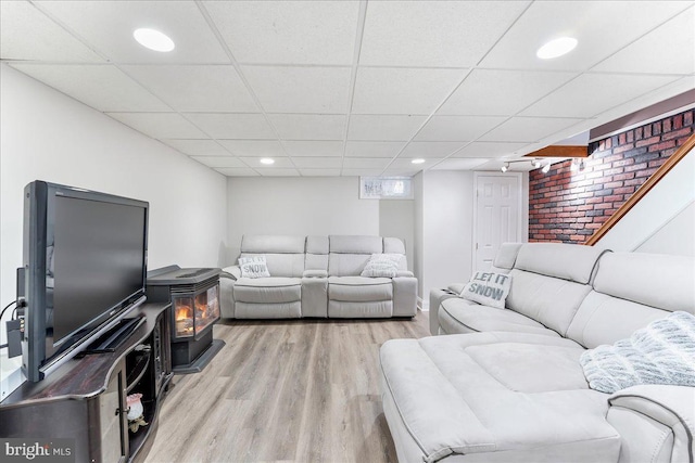 living room featuring a paneled ceiling, wood finished floors, a wood stove, and recessed lighting