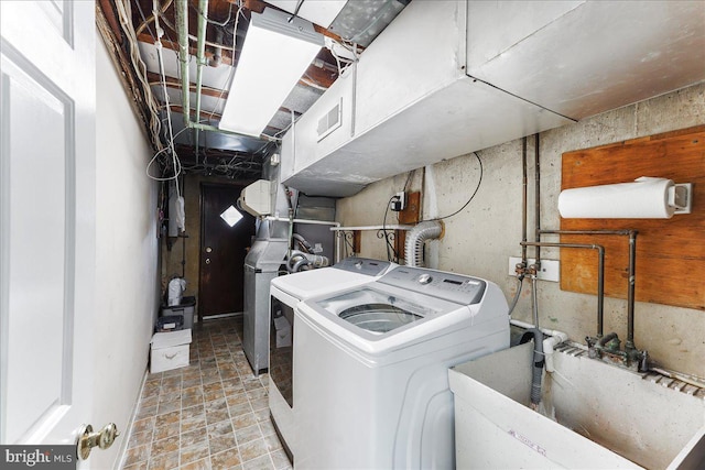 clothes washing area featuring laundry area, visible vents, separate washer and dryer, and a sink