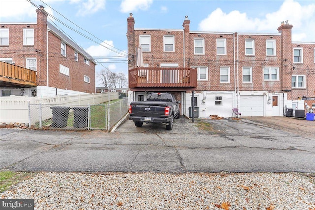 back of property with a gate, fence, a garage, cooling unit, and driveway