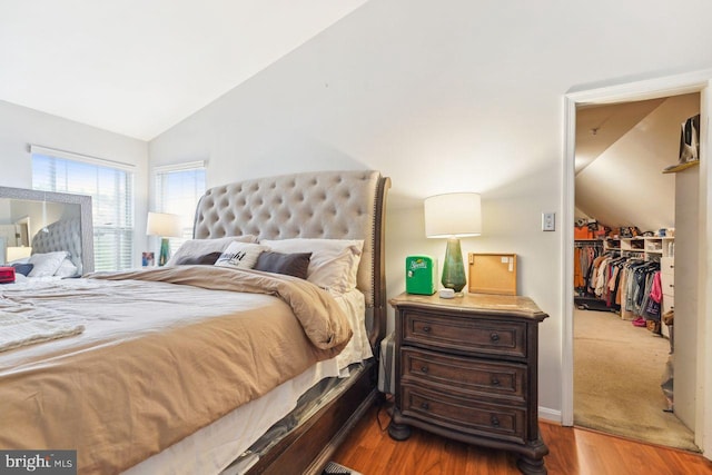 bedroom featuring lofted ceiling, a spacious closet, wood finished floors, and a closet