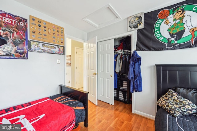 bedroom with attic access, wood finished floors, and a closet