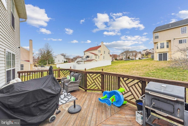 deck with grilling area, a residential view, and a lawn