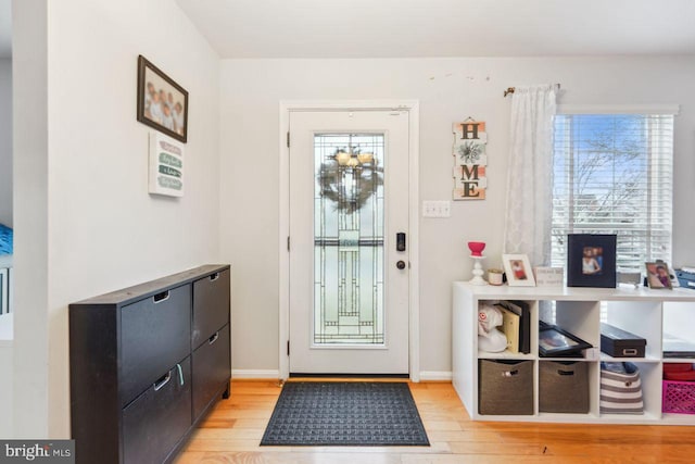 doorway to outside featuring baseboards and light wood-style floors