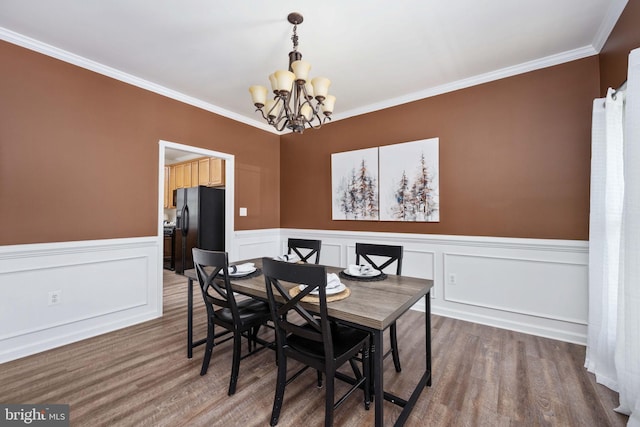 dining area featuring a chandelier, ornamental molding, and wood finished floors