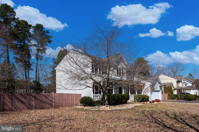 view of front facade featuring a garage, concrete driveway, and fence