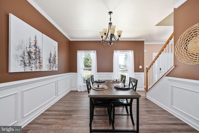 dining room with dark wood-type flooring, stairway, an inviting chandelier, wainscoting, and crown molding